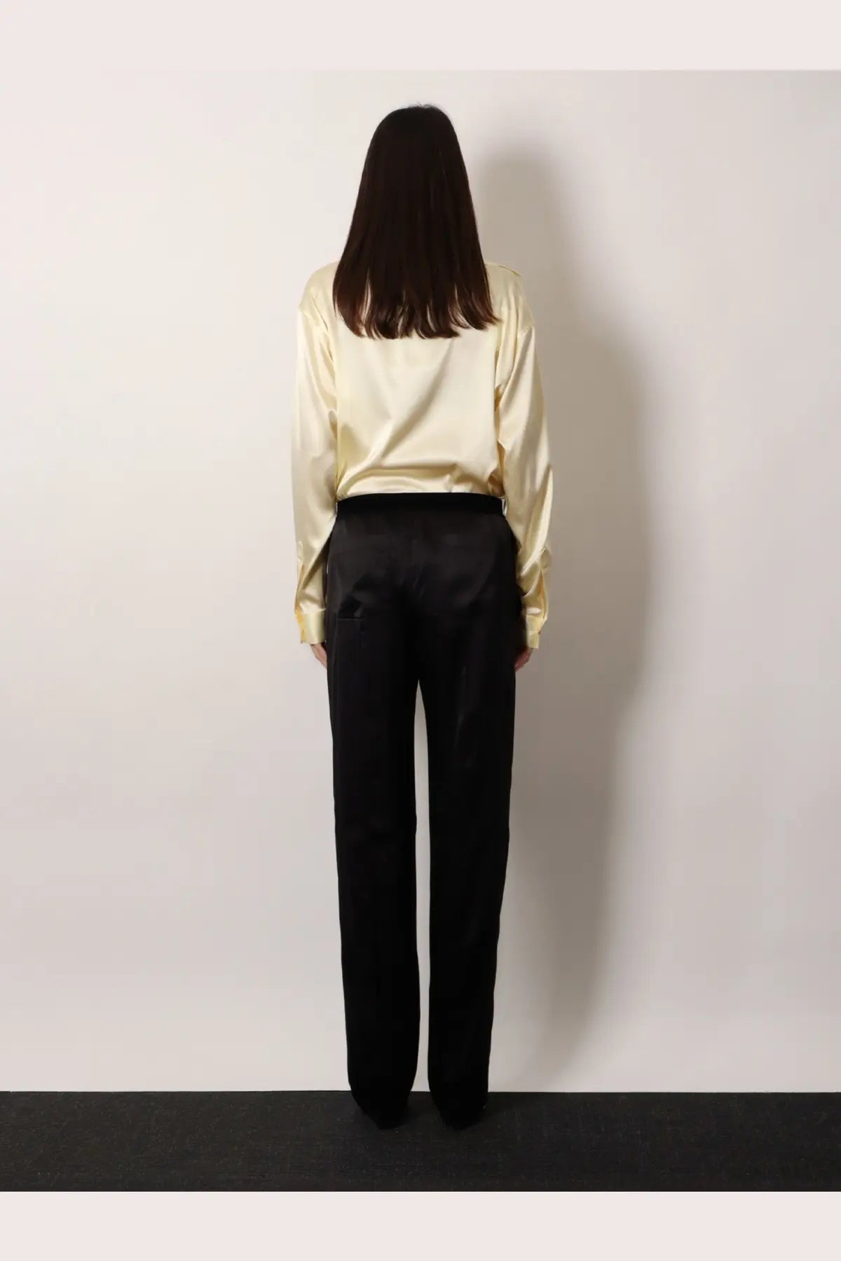 A woman wearing tom ford women’s pyjamas stretch satin black trousers paired with a cream satin blouse