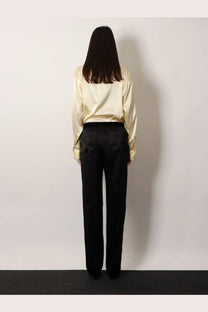A woman wearing tom ford women’s pyjamas stretch satin black trousers paired with a cream satin blouse
