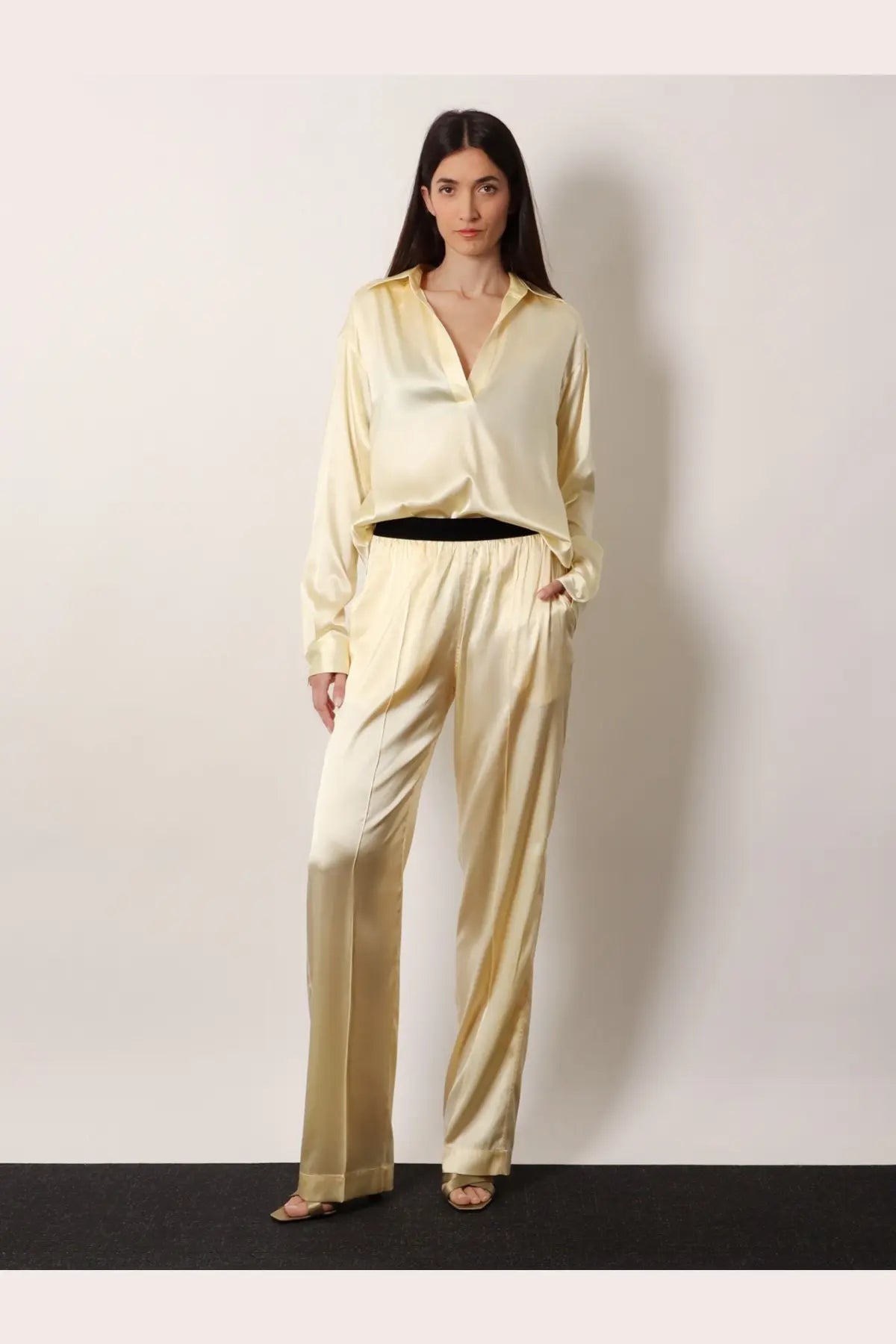 A woman wears tom ford women’s pyjamas stretch satin yellow trousers with a matching pale gold satin button-up shirt