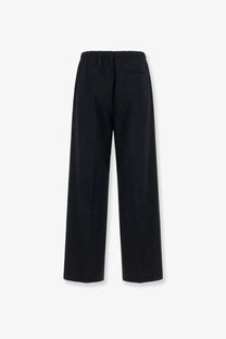 Black wide-leg wool blend trousers for men by tonywack with elastic waistband and subtle back pocket shown from the back