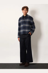 A navy and gray plaid woolen cardigan with button-front closure paired with tonywack unisex blue cotton trousers