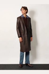 Tonywack unisex flared leg jeans in blue paired with a sleek dark brown leather overcoat with a blue and white striped collar