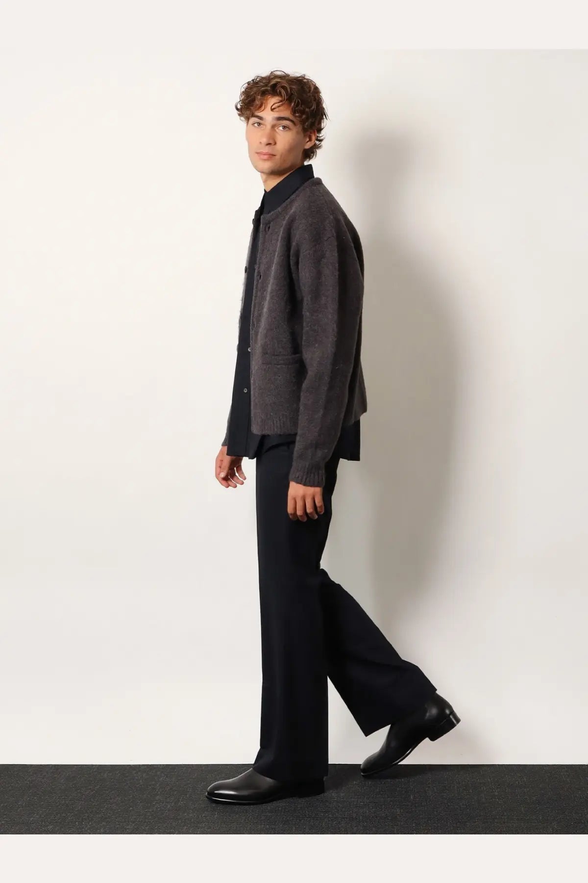 Dark gray textured knit cardigan with classic collar and button closure paired with blue wool blend pinstriped trousers