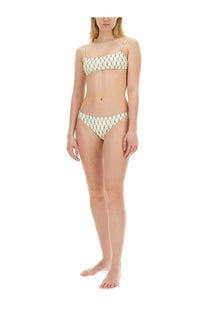 A woman wears tory burch women’s bikini briefs green with thin straps and an intricate cream and green geometric pattern