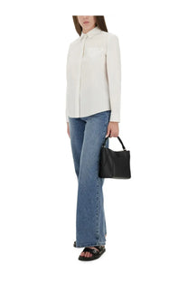 Black leather handbag with structured rectangular shape and top handle shown with tory burch women’s cotton poplin shirt white