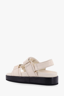 Tory Burch women’s Kira low cream leather sandals with black platform sole and gold-tone buckles