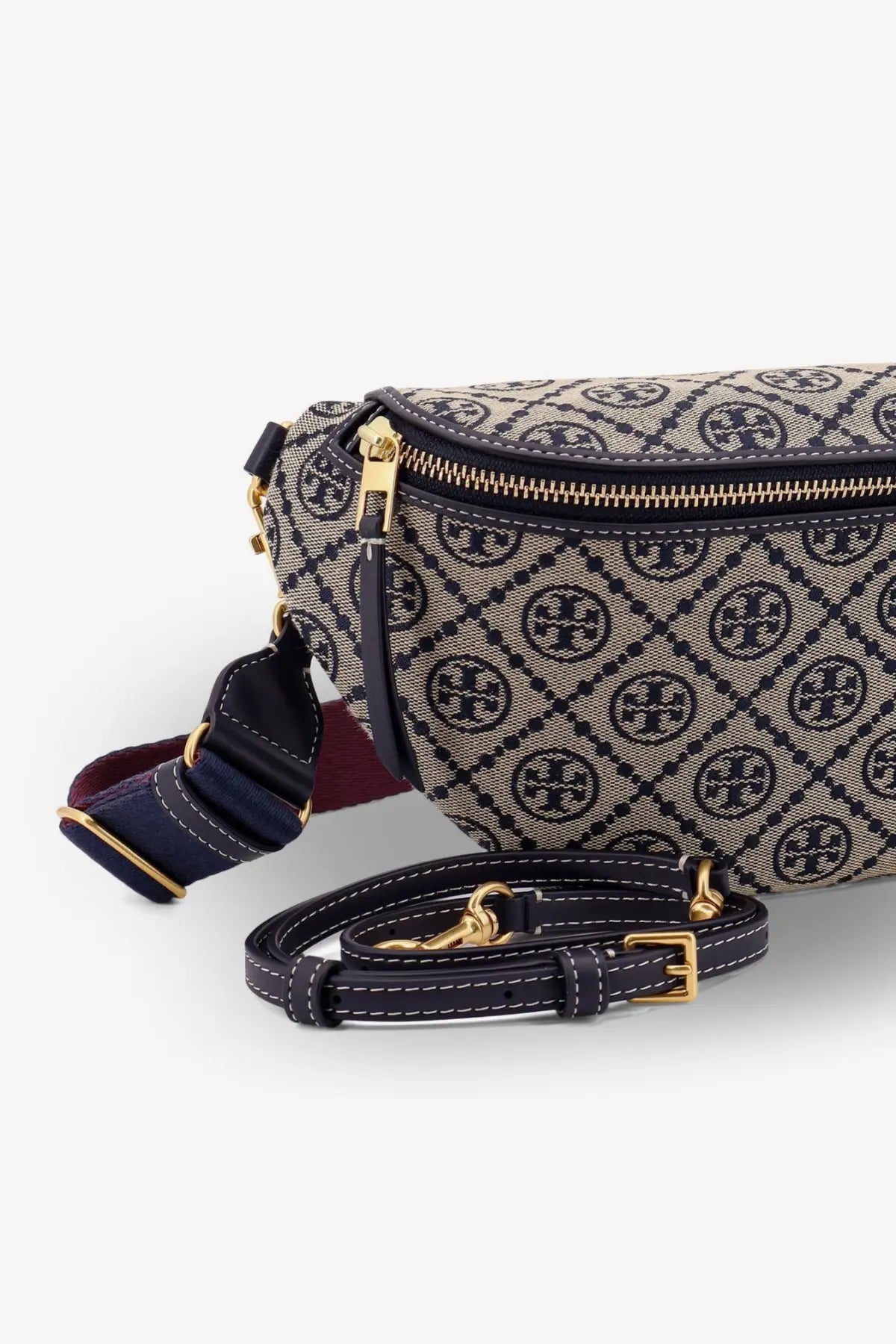 Tory Burch women’s monogram belt bag with beige and navy canvas body, gold hardware, and dark navy leather straps