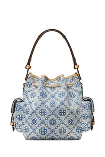 Light blue denim tory burch women’s bucket bag with navy logo pattern and brown leather handles