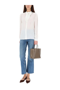 Minimalist taupe leather tote bag with structured handles and modern design shown with Tory Burch womens shirt white