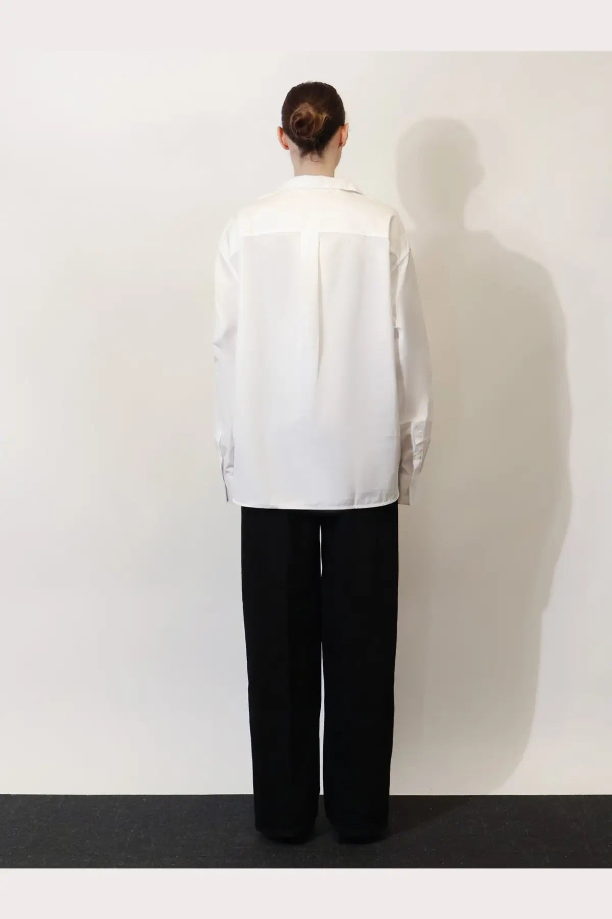 A minimalist white button-up shirt with a relaxed fit and subtle front panel worn with toteme women’s black denim jeans black