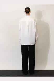 A minimalist white button-up shirt with a relaxed fit and subtle front panel worn with toteme women’s black denim jeans black