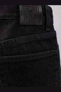 Toteme womens black denim jeans in dark wash with visible stitching and branded leather patch at the waistband back view