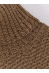 A close-up of a camel-colored ribbed knit cashmere turtleneck sweater with a textured interlocking stitch pattern by Toteme