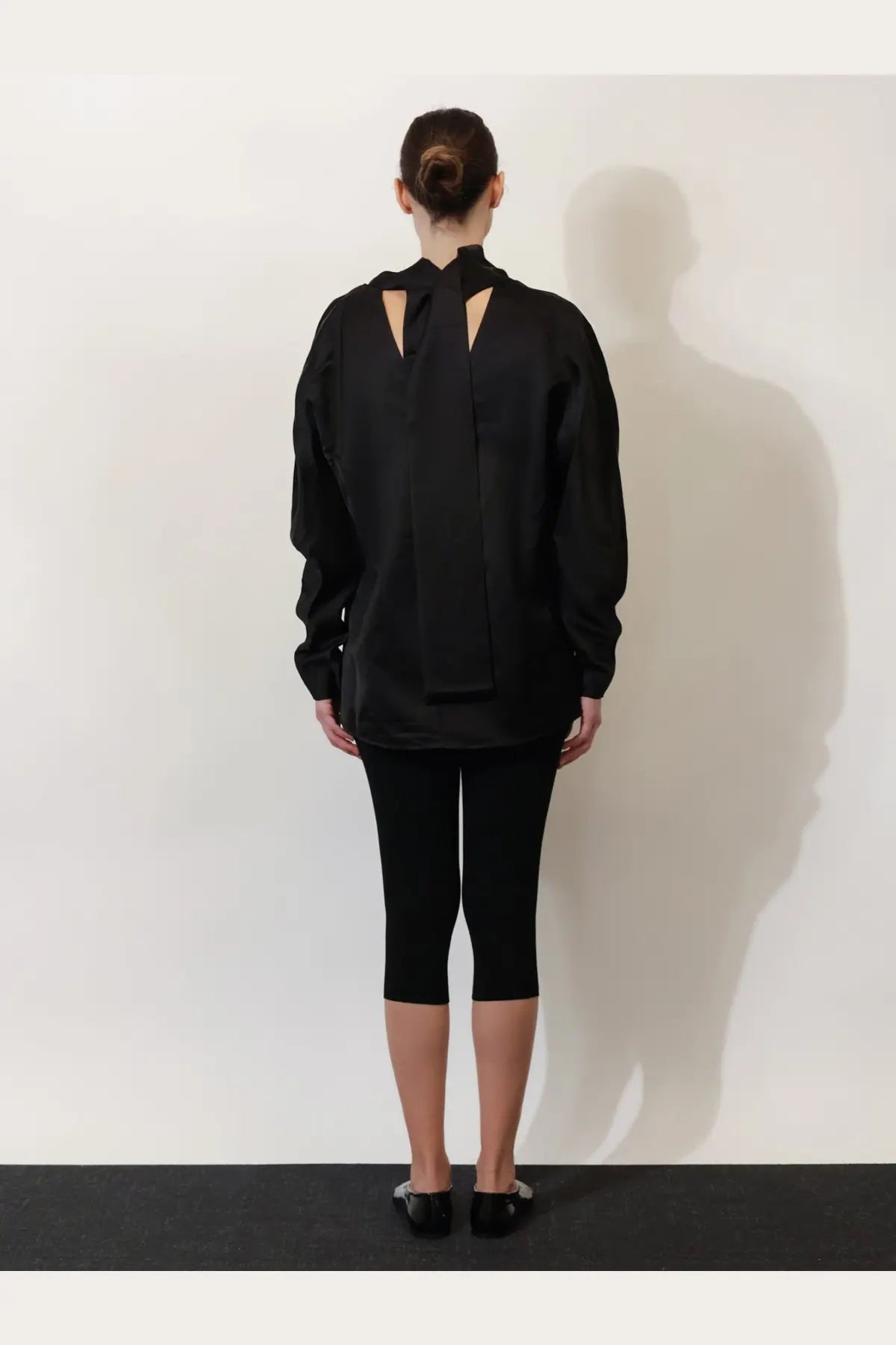 Black oversized viscose and linen blouse by toteme with a distinctive cutout back design shown from the back side