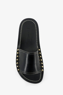 Toteme women’s low black leather slide sandal with gold-tone studs and white stitching on the strap