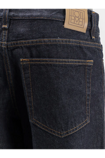 Toteme women’s low straight denim jeans in dark indigo with tan stitching and a brown leather brand patch on the back waistband