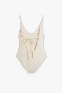 Cream-colored Toteme women’s nylon scoop one piece swimsuit with thin spaghetti straps and back tie detail shown from back