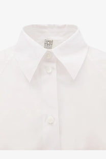 Toteme women’s white organic cotton shirt with crisp collar subtle texture and Loewe logo tag at the neck