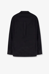 Back view of toteme women’s oversized black cotton shirt with subtle vertical seam and buttoned cuffs