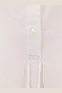 A delicate white button with subtle sheen on the textured fabric of a toteme women’s stand collar organic cotton shirt white