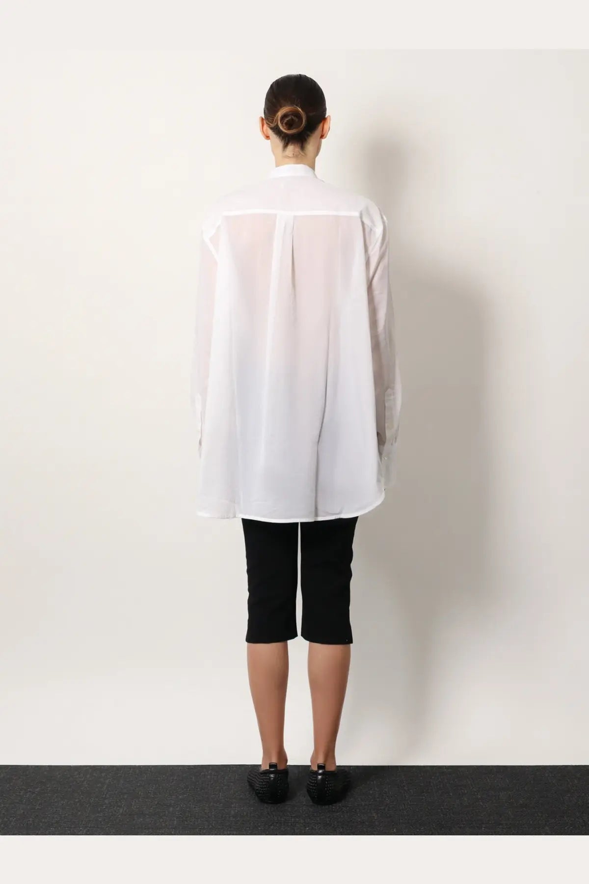 Toteme women’s stand collar organic cotton white shirt translucent with long sleeves worn over black capri pants