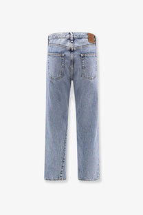 Back view of toteme women’s twisted seam light-wash organic cotton jeans with straight legs and brown leather patch