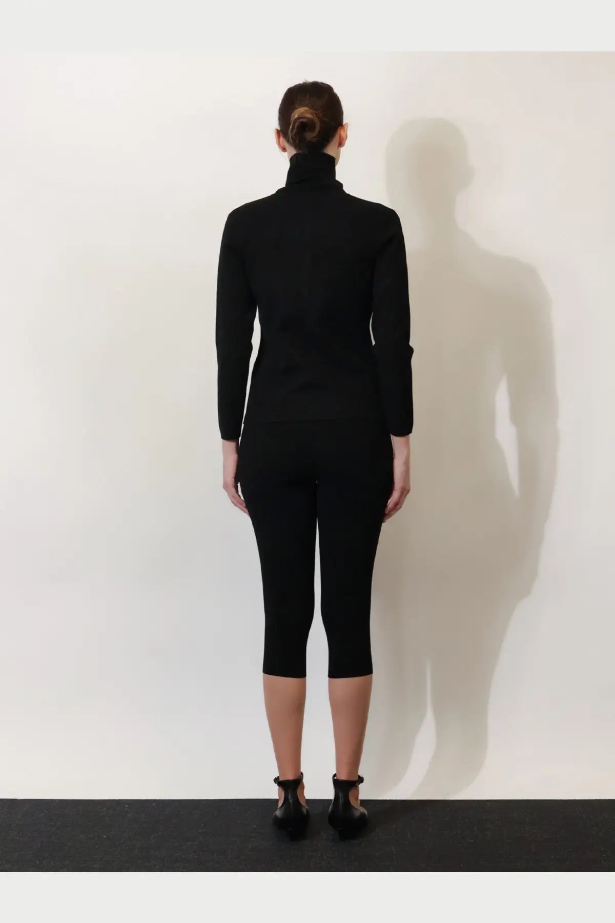 Toteme women’s black viscose blend cardigan styled with a sleek high-neck knit top and capri pants in minimalist look