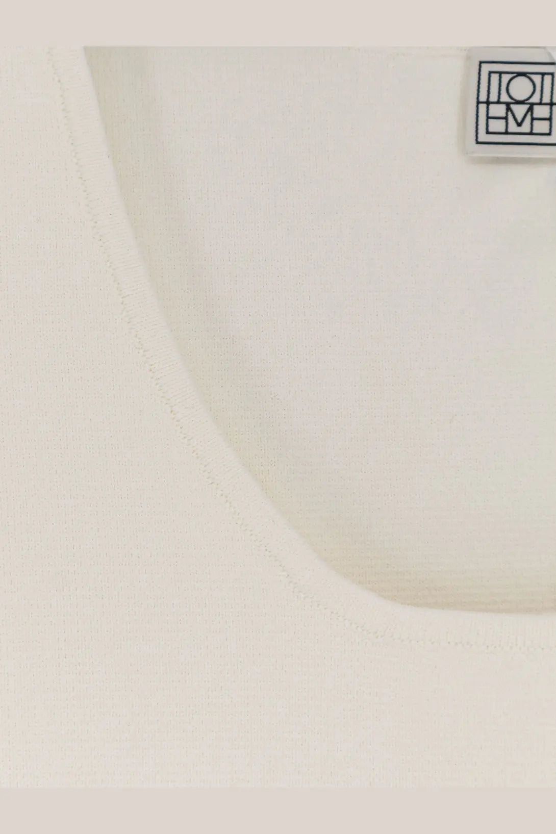 Toteme women’s white cotton tank top with minimalist black logo patch on the upper right side