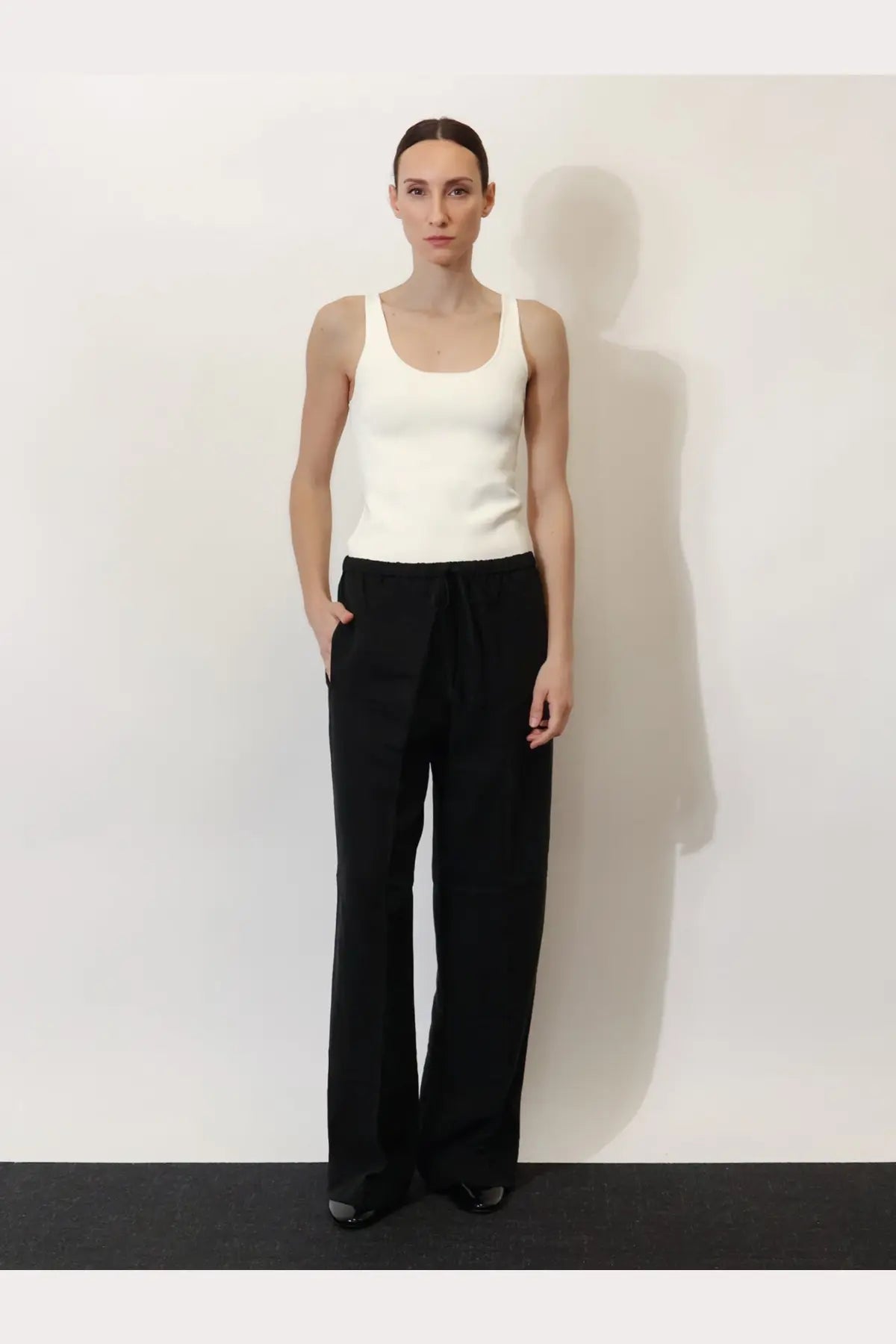 Minimalist black wide-leg pants with drawstring waistband paired with toteme women’s white viscose blend tank top