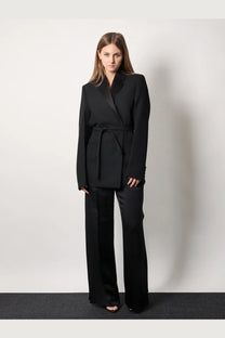 Black tailored blazer with belted waist paired with wide-leg viscose blend trousers from Toteme women’s collection