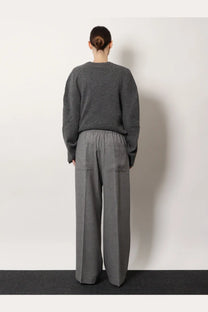 Gray textured knit sweater with relaxed fit and long sleeves paired with toteme women’s viscose grey trousers