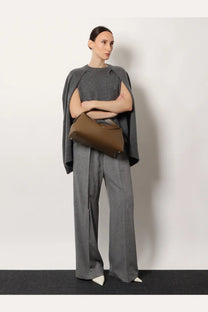 A structured olive green leather handbag with minimalist design and metallic hardware paired with toteme grey viscose trousers