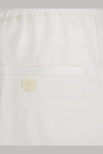 Toteme women’s white viscose trousers with subtle pleated waistband and single button closure visible from the back