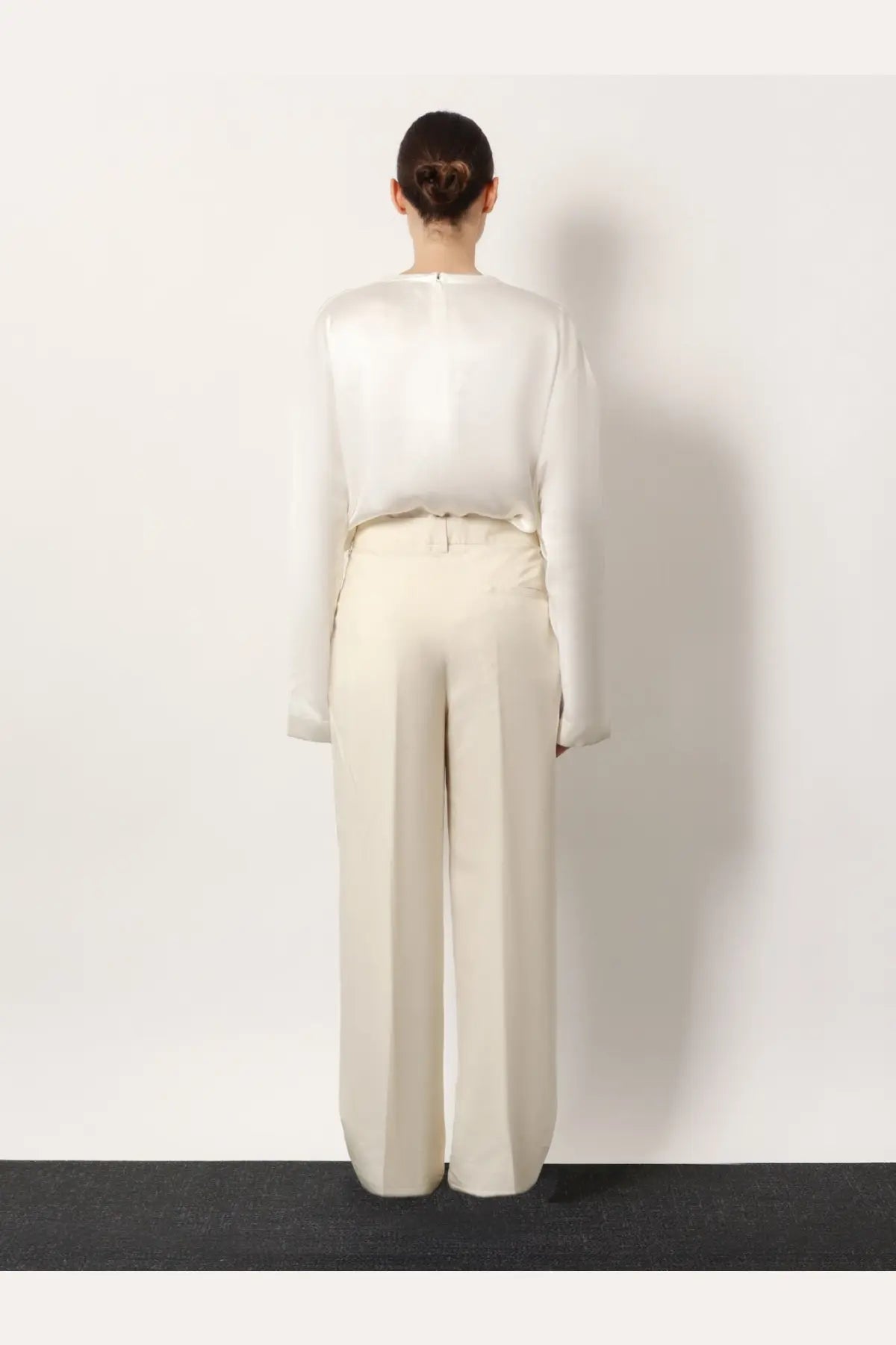 A woman wearing toteme women’s white viscose trousers paired with a minimalist white long sleeve blouse