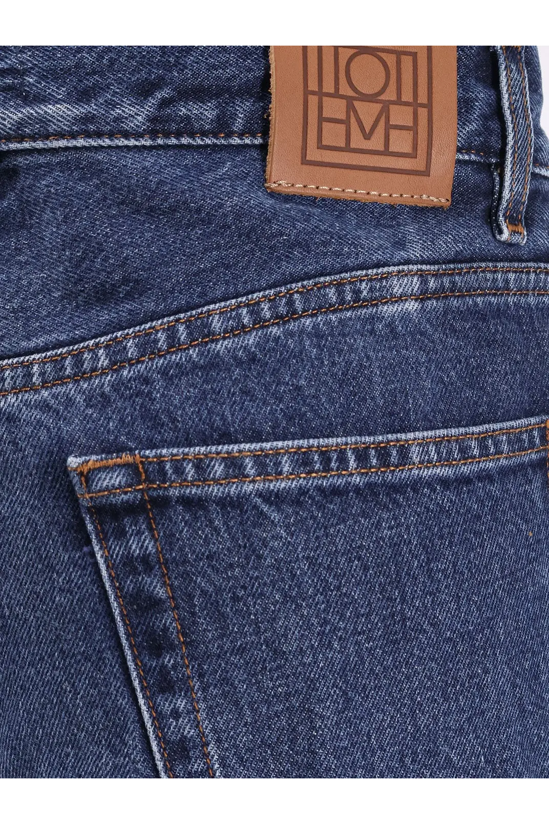 Dark blue Toteme women’s wide leg organic cotton jeans showing back with brown leather brand patch embossed lettering