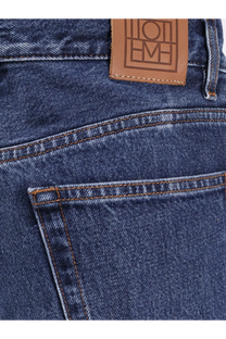 Dark blue Toteme women’s wide leg organic cotton jeans showing back with brown leather brand patch embossed lettering