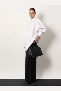 Black leather handbag with structured shape and top handles paired with toteme women’s wool trouser black