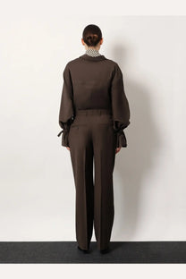 Brown linen jumpsuit with tied cuffs and collar paired with toteme women’s grey wool trousers