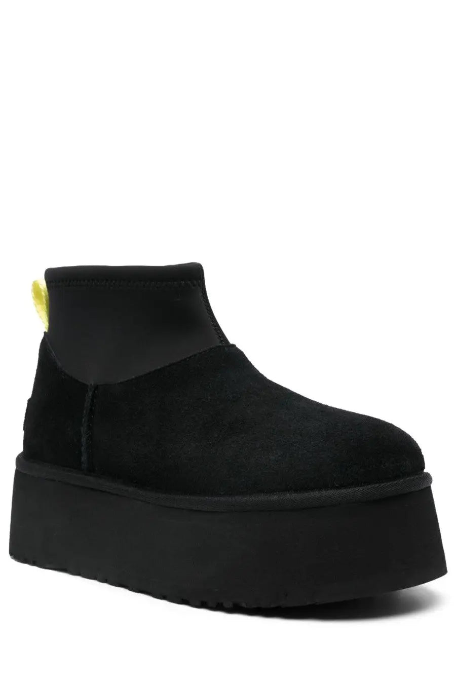 Ugg women’s classic mini dipper black boot in black suede with thick platform sole and yellow pull tab shown from back