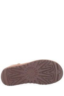Back view of ugg women’s classic ultra mini beige boot with brown rubber sole and geometric tread pattern