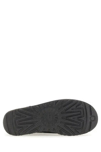 Black rubber sole of ugg women’s boot classic ultra mini black with embossed ugg logo and textured tread pattern