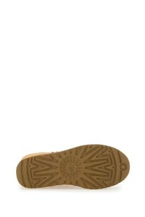 Backside of ugg women’s classic tall brown boot showing tan rubber sole with geometric tread and ugg logo near heel