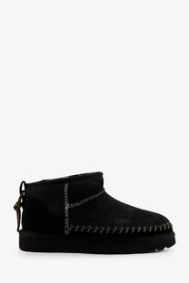 Ugg women’s classic ultra mini biarritz black suede ankle boot with silver stitching and back pull tab shown from rear