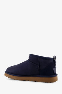 Navy blue suede ugg women’s classic ultra mini boots with tan rubber sole and back pull tab shown from behind