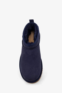 Navy blue suede UGG women’s classic ultra mini ankle boot with plush shearling lining and tan rubber sole