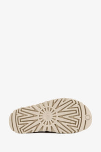 Ugg women’s beige rubber sandals showing a beige rubber sole with sunburst tread pattern and embossed ugg logo