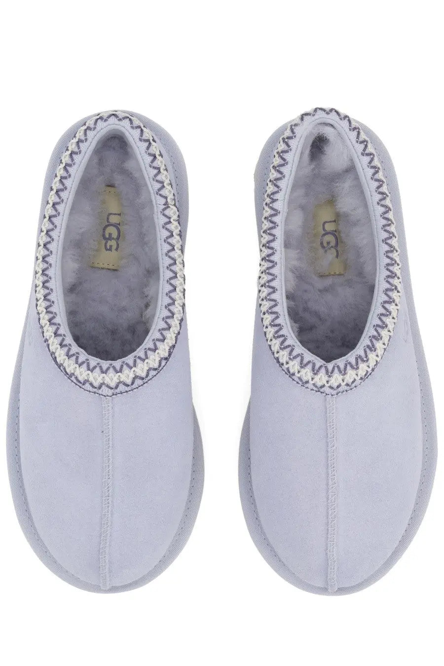 Light gray ugg women slip-on tasman slippers with soft fuzzy interior and decorative zigzag stitching along the opening
