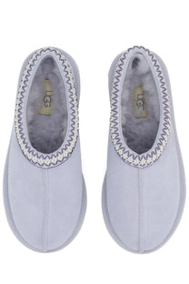 Light gray ugg women slip-on tasman slippers with soft fuzzy interior and decorative zigzag stitching along the opening