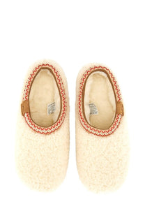 Cream-colored ugg women’s tasman white sheepskin slip-on slippers with red and beige woven trim around the opening