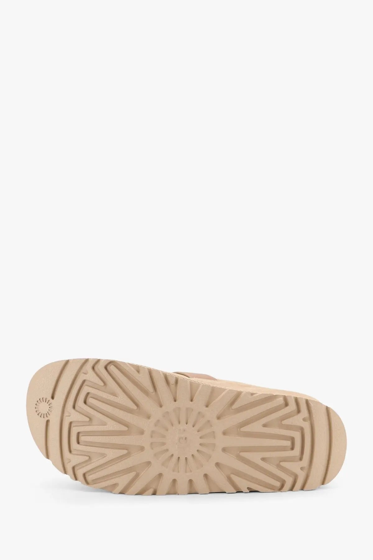 Back sole of beige ugg women’s suede sandals featuring a radiating tread pattern and embossed brand logo near heel